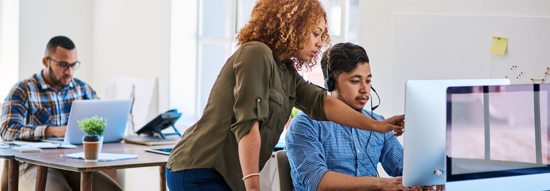 Female worker directing young intern on computer