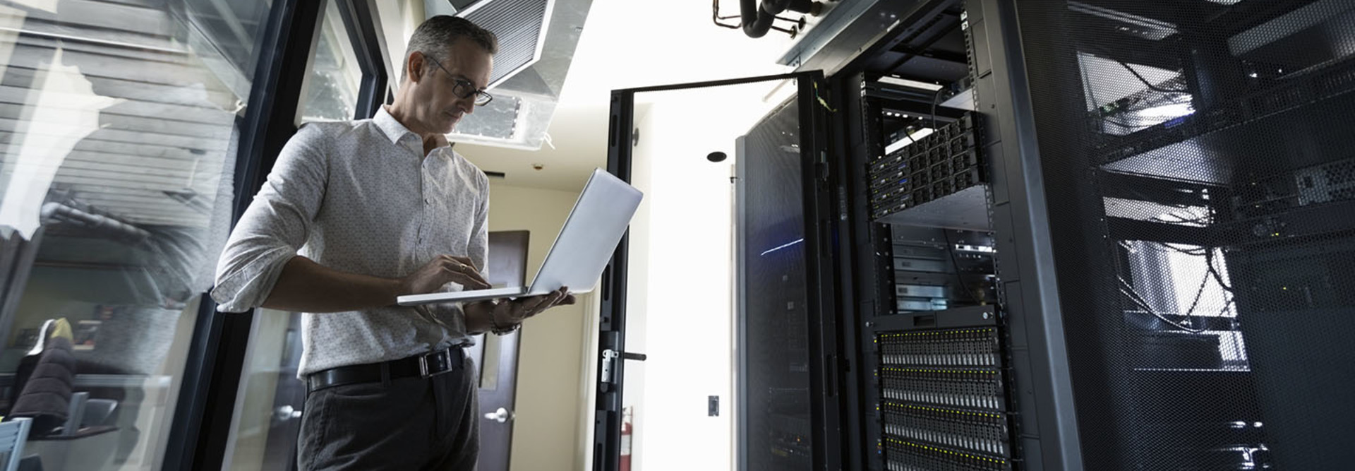 Male Caucasian IT technician using laptop in server room