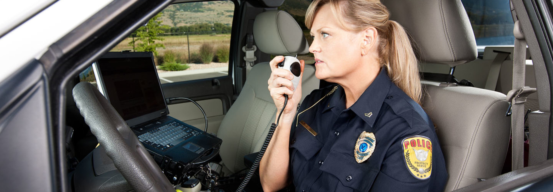 Female Police Officer Talking on Radio in Vehicle