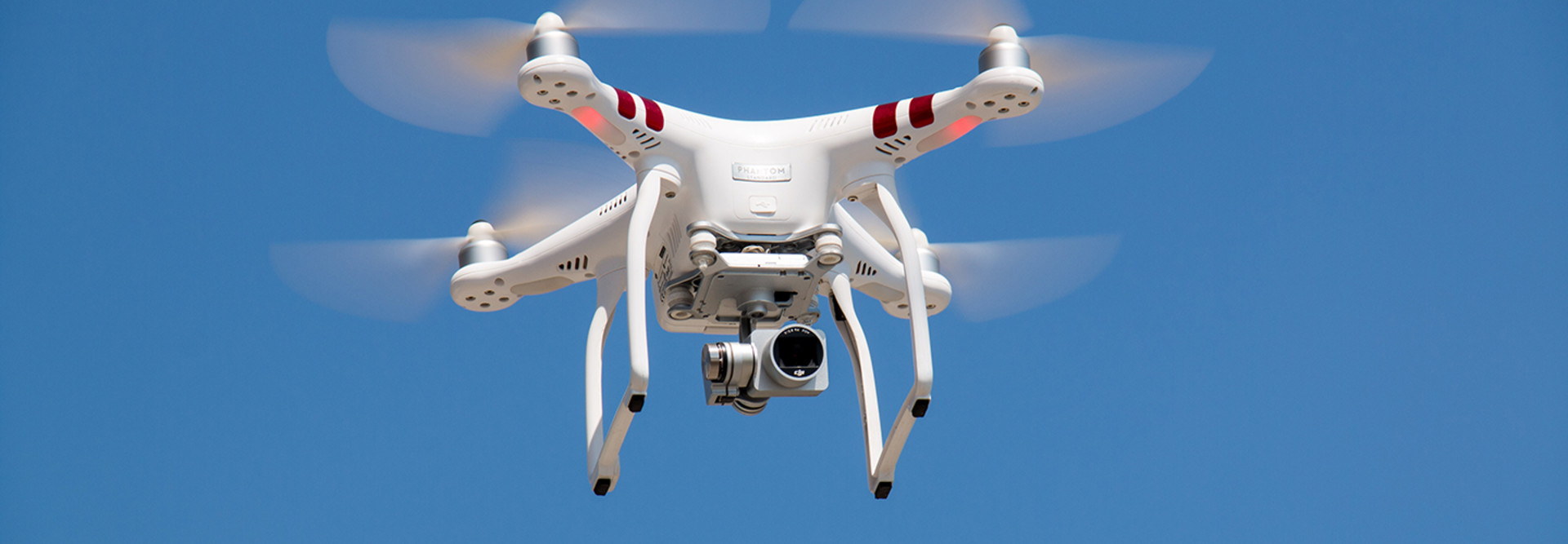 Drone with a camera flying on a blue sky 