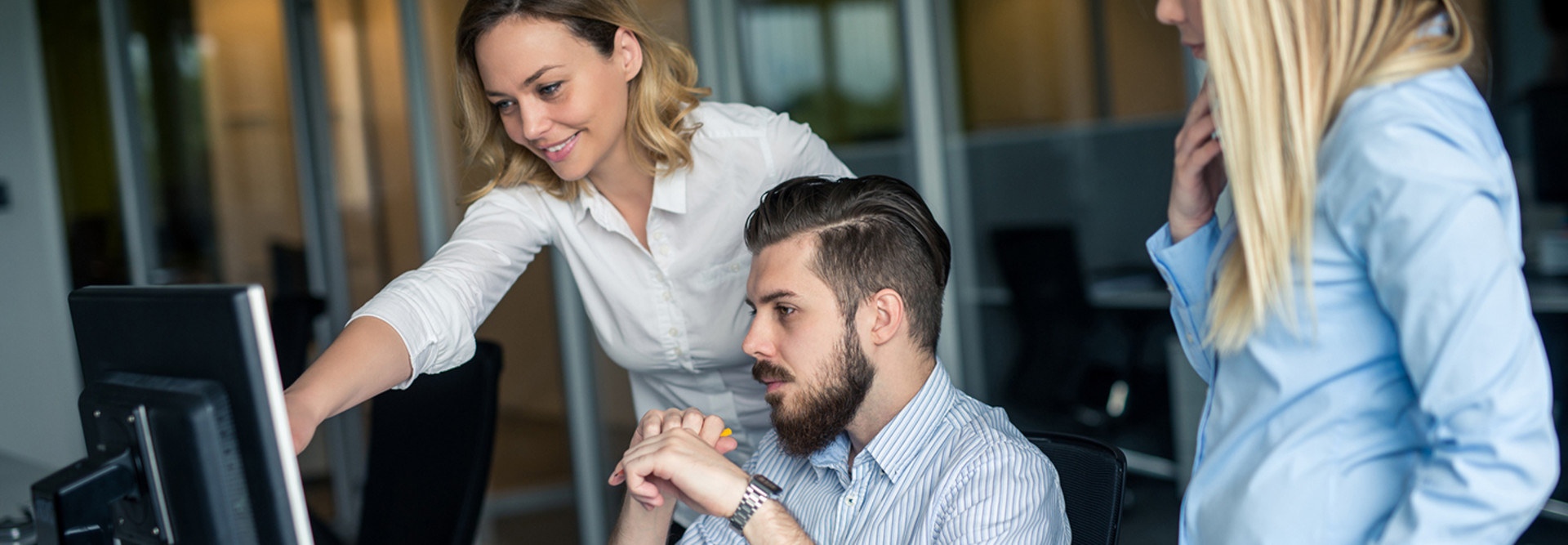 Woman training male colleague on cybersecurity at a computer screen
