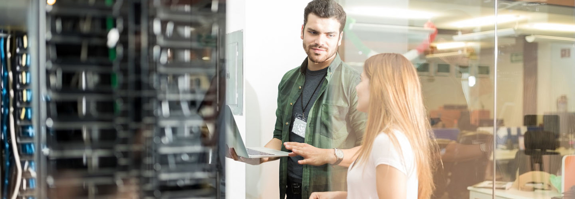 Two business people standing in server room with laptop and discussing