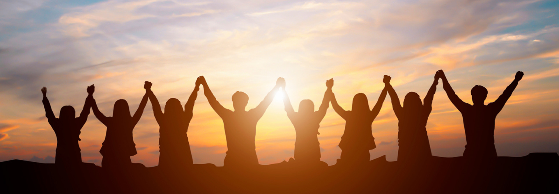 Team holding hands with a sunset in the background 