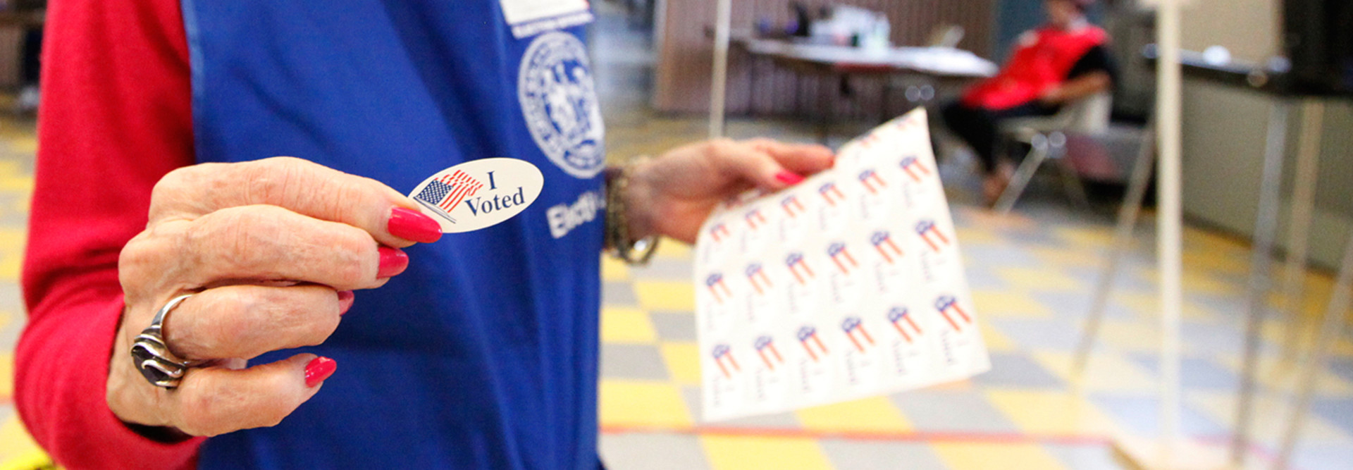 Woman handing out an I voted sticker on Election Day 