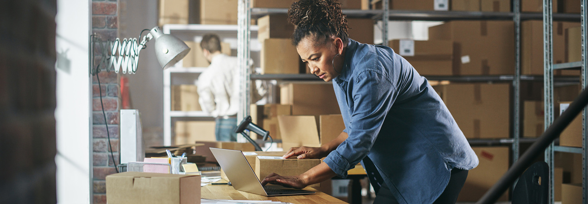 Warehouse Female Inventory Manager Works on Laptop Computer while Standing at Her Desk.