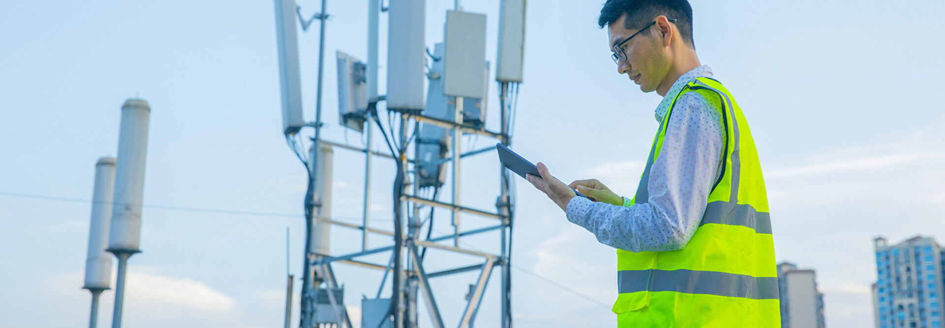 Engineer working on a digital tablet near communications tower