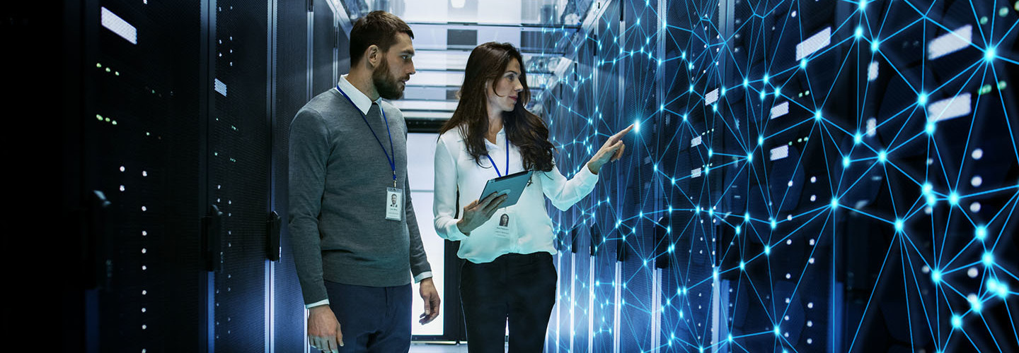 Female and Male IT Engineers Discussing Technical Details in a Working Data Center/ Server Room with Internet Connection Visualization.