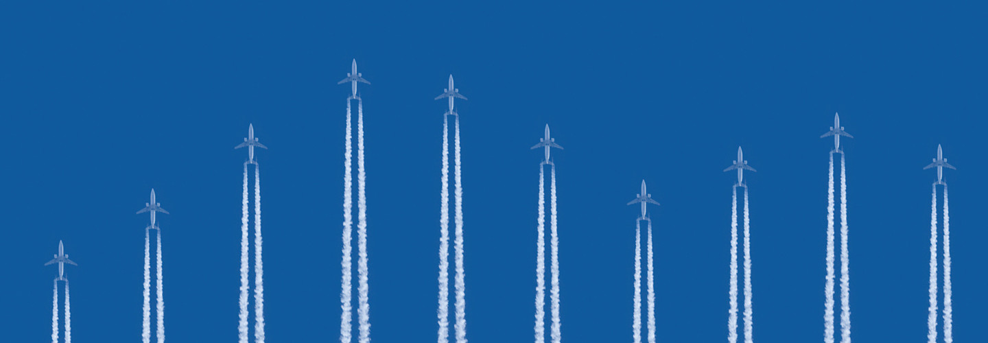 Airplanes flying vertically on a blue background with contrails below them 