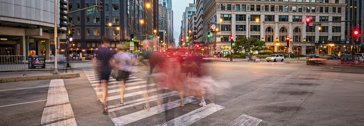People walking across a cross-walk in Chicago at dusk 