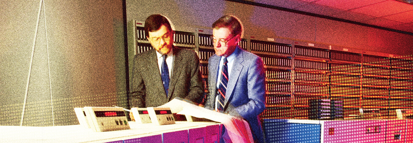 Two men working on mainframe computers in the 1980s 