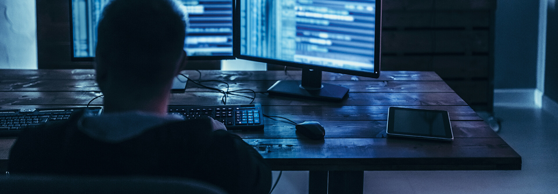 Man examining blurred code in a dark room