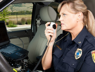 Female Police Officer Talking on Radio in Vehicle
