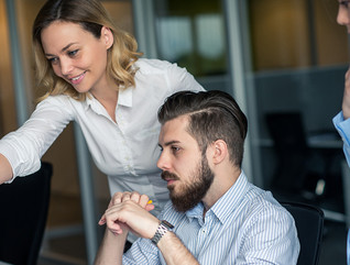 Woman training male colleague on cybersecurity at a computer screen