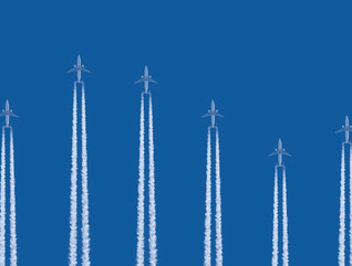 Airplanes flying vertically on a blue background with contrails below them 