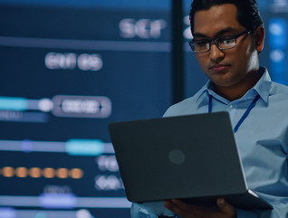 Professional looking at data holding laptop