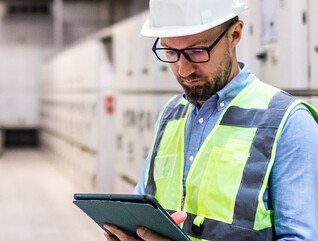 Electrical engineer in control room using digital tablet