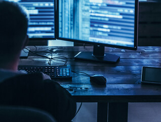 Man examining blurred code in a dark room