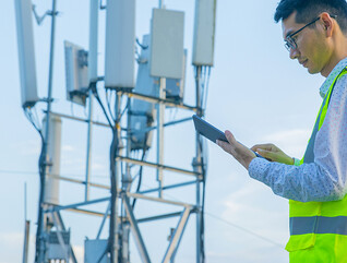 Engineer working on a digital tablet near communications tower