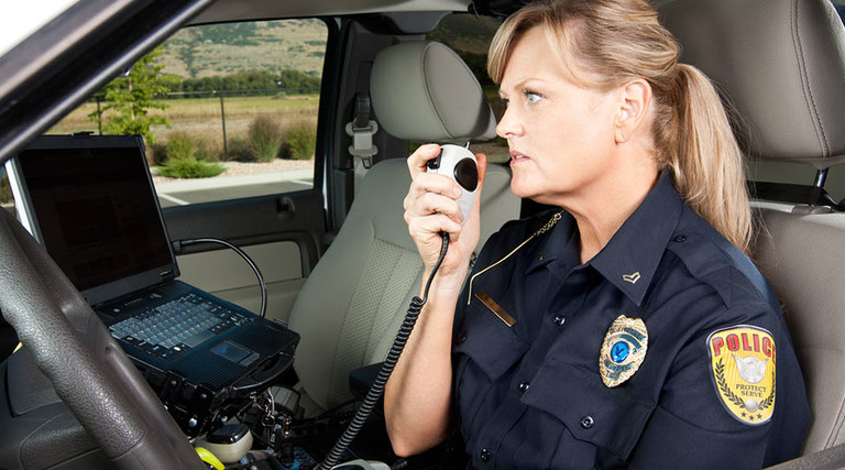 Female Police Officer Talking on Radio in Vehicle
