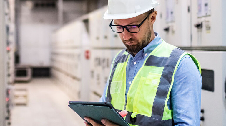 Electrical engineer in control room using digital tablet