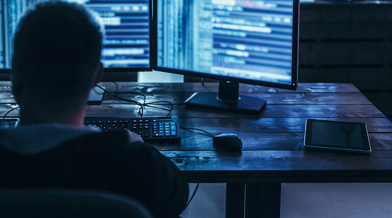 Man examining blurred code in a dark room