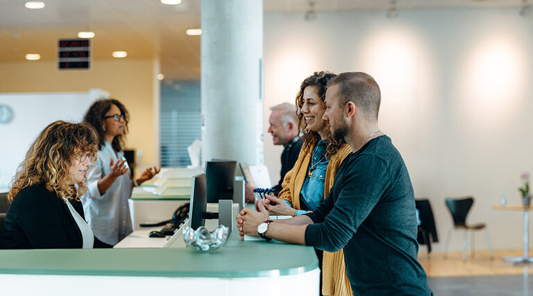 People speaking to receptionist