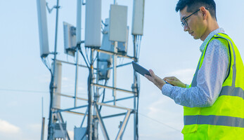 Engineer working on a digital tablet near communications tower
