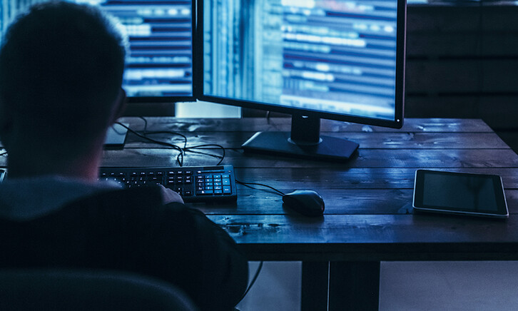 Man examining blurred code in a dark room