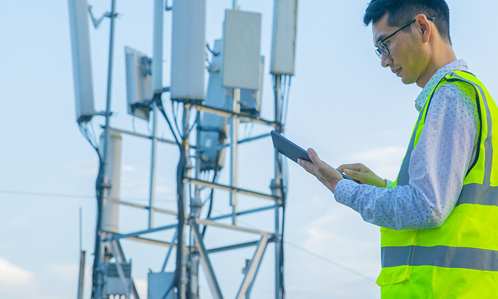 Engineer working on a digital tablet near communications tower