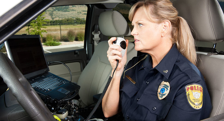 Female Police Officer Talking on Radio in Vehicle