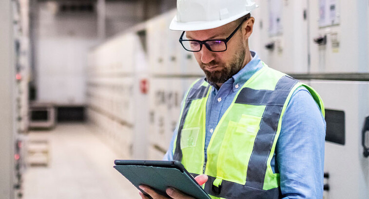Electrical engineer in control room using digital tablet