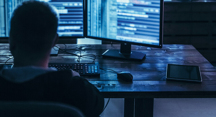 Man examining blurred code in a dark room