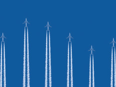 Airplanes flying vertically on a blue background with contrails below them 