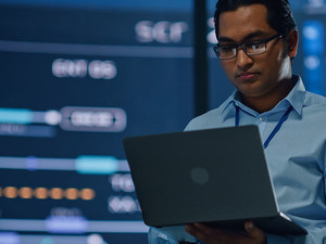 Professional looking at data holding laptop